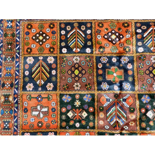 73 - A Bakhtiari design rug, decorated with a chequerboard of floral and geometric motifs, on a multi-col... 