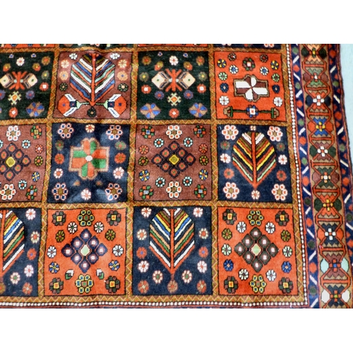 73 - A Bakhtiari design rug, decorated with a chequerboard of floral and geometric motifs, on a multi-col... 