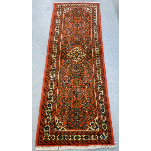 76 - A Hamadan design runner, decorated with a central medallion and floral motifs, on a red ground ... 