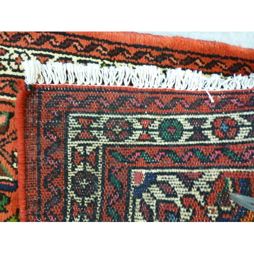 76 - A Hamadan design runner, decorated with a central medallion and floral motifs, on a red ground ... 