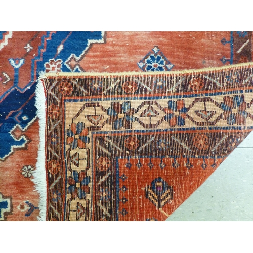 319 - A Persian rug, decorated with floral motifs, on a red and blue ground  72