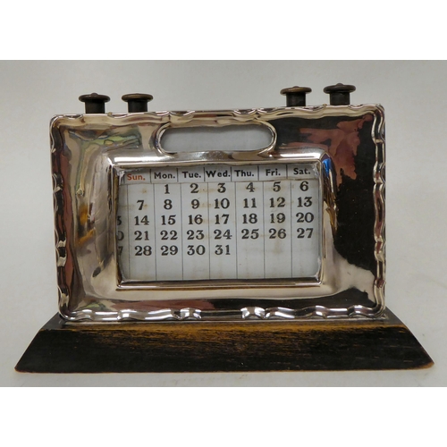 10 - An Edwardian desktop aneroid barometer, in a decoratively pressed, silver frame, on an oak mount and... 