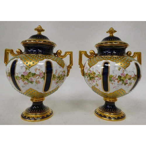 20 - A pair of 20thC Coalport china, twin handled pedestal vases and covers, in midnight blue and gilding... 