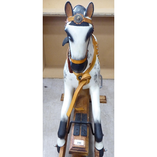 248 - An early 20thC overpainted nursery rocking horse, on an oak plinth  38