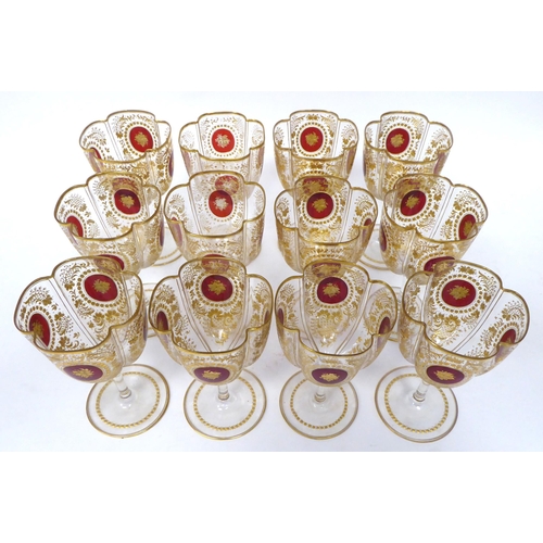 47 - A set of twelve late 19th/early 20thC lobed pedestal wine glasses, decorated with cranberry medallio... 