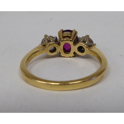 59 - A gold coloured metal ring, claw set with a diamond and a ruby 