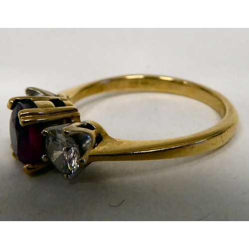 59 - A gold coloured metal ring, claw set with a diamond and a ruby 