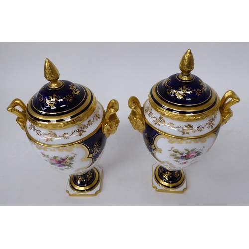 61 - A 20thC pair of Coalport china, ovoid shape, pedestal vases with covers and opposing ram's head hand... 