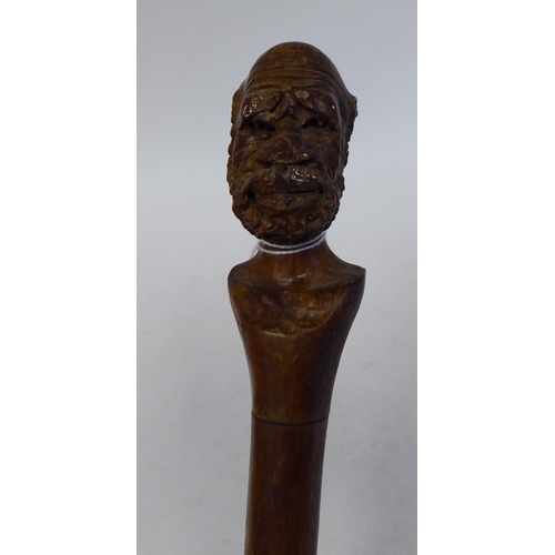 95 - An Aboriginal hardwood walking stick, the terminal fashioned as a finely carved man's head  40