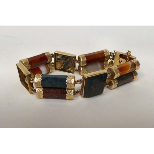 96 - A Scottish coloured hardstone and gold coloured metal tablet and cylinder link bracelet, on a bayone... 