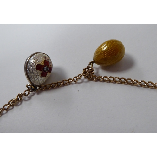 99 - A Russian egg necklace, including three pre-revolution 1900-1910 Faberge by the Workmaster Feodor At... 