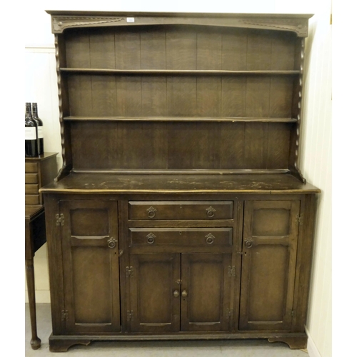 253 - A 20thC stained oak cottage dresser, the upper section with two open plate rack shelves, over two dr... 