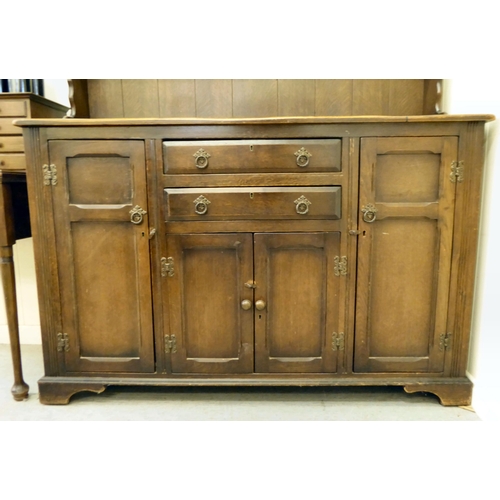 253 - A 20thC stained oak cottage dresser, the upper section with two open plate rack shelves, over two dr... 