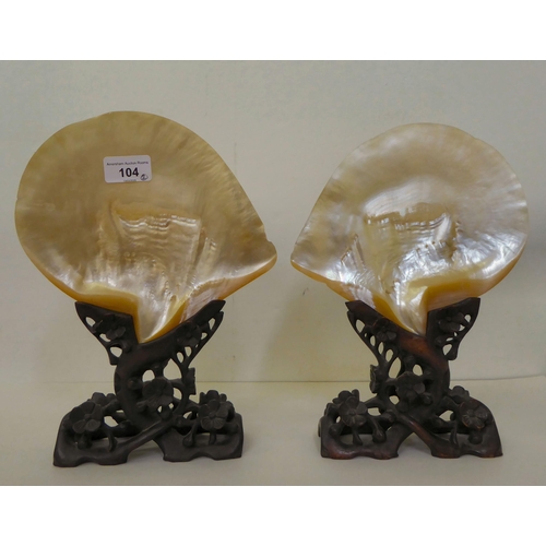 104 - A pair of early 20thC Chinese mother-of-pearl shell ornaments, each with a prunus carved softwood st... 