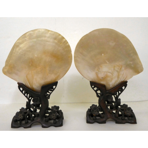 104 - A pair of early 20thC Chinese mother-of-pearl shell ornaments, each with a prunus carved softwood st... 