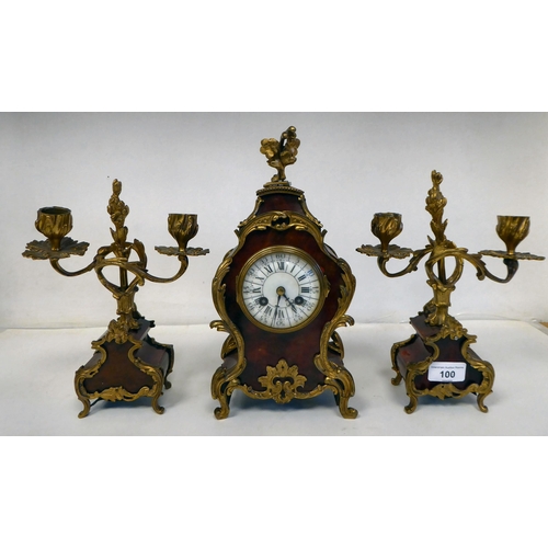 100 - A late 19thC French gilt metal mounted and laminated, three piece clock garniture with ornately cast... 