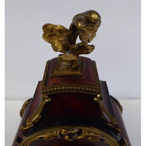 100 - A late 19thC French gilt metal mounted and laminated, three piece clock garniture with ornately cast... 