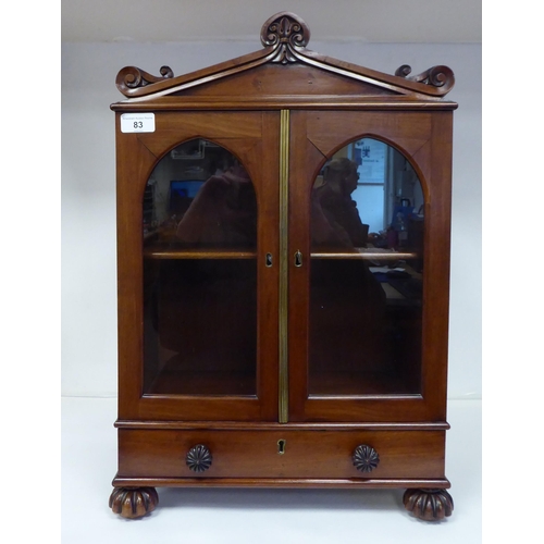 83 - A William IV mahogany, lockable table cabinet, the pointed arched top with carved ornament, over a p... 