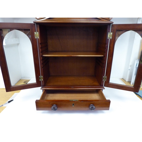 83 - A William IV mahogany, lockable table cabinet, the pointed arched top with carved ornament, over a p... 
