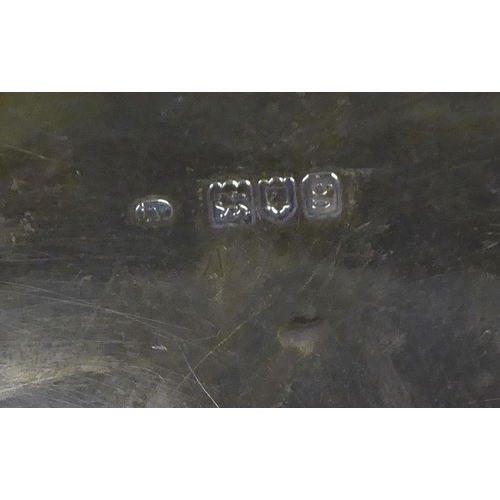 97 - An Edwardian silver waiter with a raised shell and scroll cast border, on conforming feet  bears a p... 