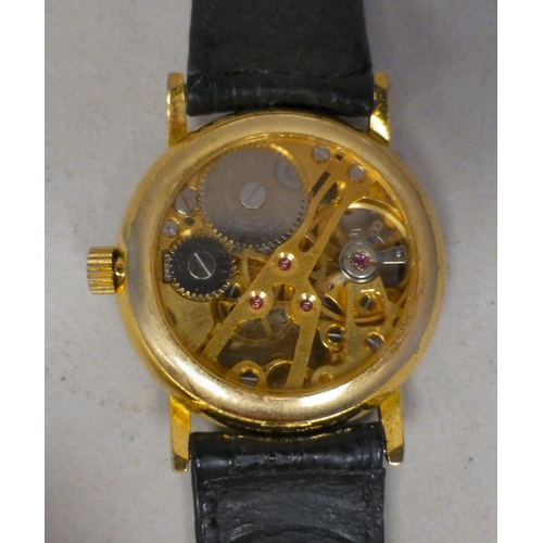 24 - A modern gold plated manual skeleton wristwatch, faced by a Roman dial