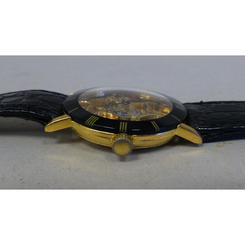 24 - A modern gold plated manual skeleton wristwatch, faced by a Roman dial