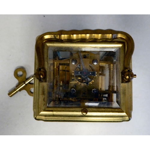 32 - A lacquered brass travel clock with bevelled glass panels; the gong strike movement faced by an enam... 