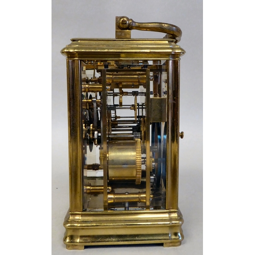 32 - A lacquered brass travel clock with bevelled glass panels; the gong strike movement faced by an enam... 