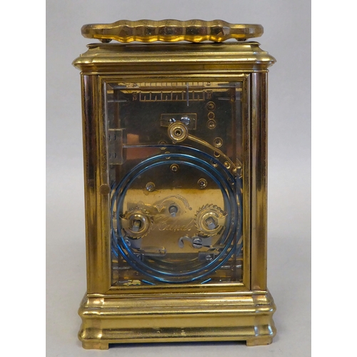32 - A lacquered brass travel clock with bevelled glass panels; the gong strike movement faced by an enam... 