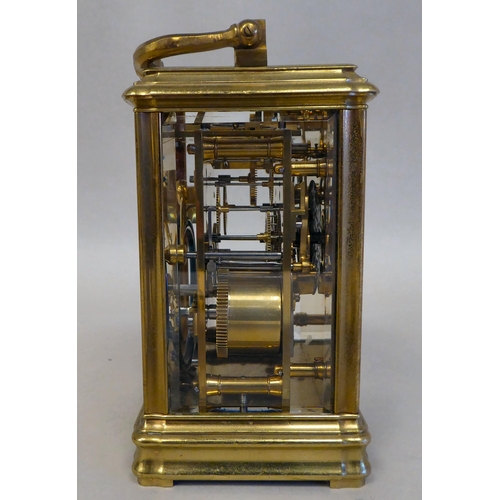 32 - A lacquered brass travel clock with bevelled glass panels; the gong strike movement faced by an enam... 
