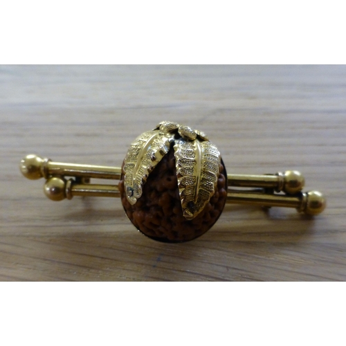 5 - A yellow metal twin bar brooch, set with a seed/shell style centre with leaf decoration&nbsp; (appro... 