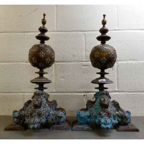 152 - A pair of late 19th/early 20thC cast bronzed fire dogs, fashioned vases with fancy rims, on a steppe... 