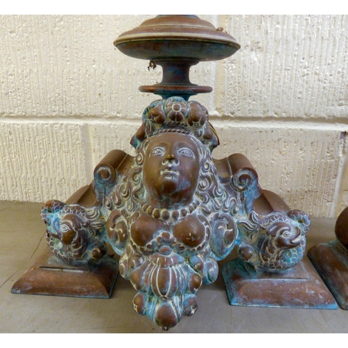 152 - A pair of late 19th/early 20thC cast bronzed fire dogs, fashioned vases with fancy rims, on a steppe... 