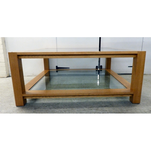 163 - A modern light oak coffee table with two inset glass panels, raised on block feet&nbsp; 20