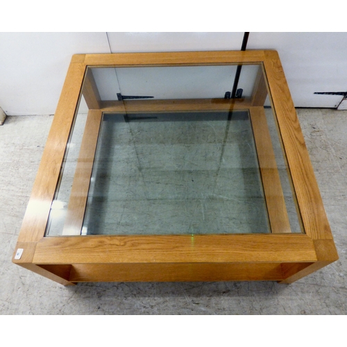 163 - A modern light oak coffee table with two inset glass panels, raised on block feet&nbsp; 20