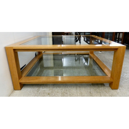 163 - A modern light oak coffee table with two inset glass panels, raised on block feet&nbsp; 20