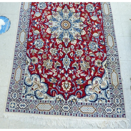 31 - A Persian rug, decorated with a central medallion, bordered by mainly floral designs, on a multi-col... 
