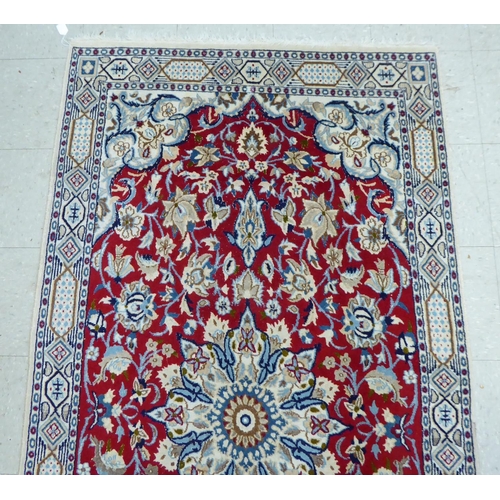 31 - A Persian rug, decorated with a central medallion, bordered by mainly floral designs, on a multi-col... 