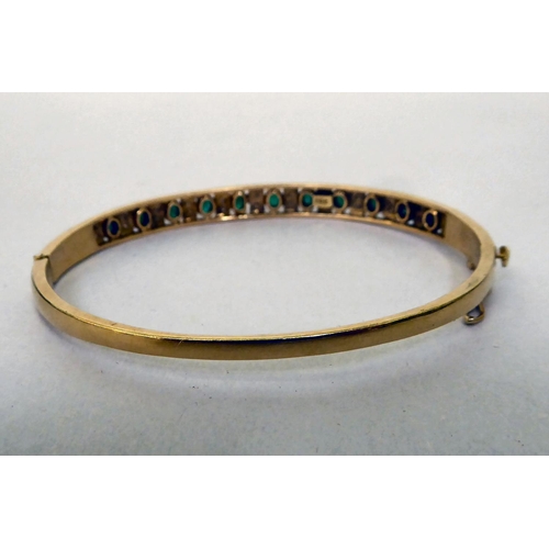 48 - A yellow metal (probably 18ct gold) hinged bangle, set with alternating emeralds and diamonds  (appr... 