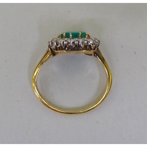 51 - A yellow metal (probably 18ct gold) cluster ring, set with a central emerald, surrounded by diamonds... 