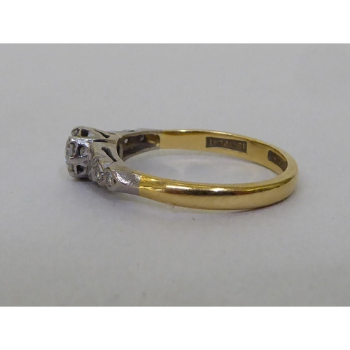 53 - A Bravington's yellow metal ring, set with a central claw set diamond, flanked by diamond chips  sta... 
