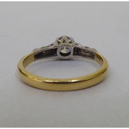 53 - A Bravington's yellow metal ring, set with a central claw set diamond, flanked by diamond chips  sta... 