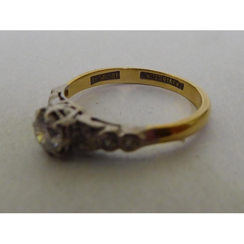 53 - A Bravington's yellow metal ring, set with a central claw set diamond, flanked by diamond chips  sta... 