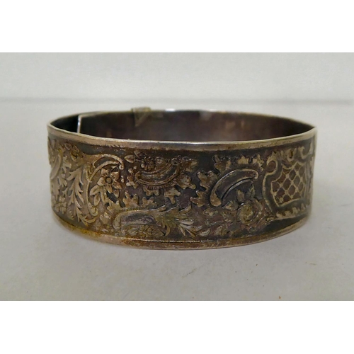 61 - A silver buckle bangle, decorated with floral motifs&nbsp; marks rubbed