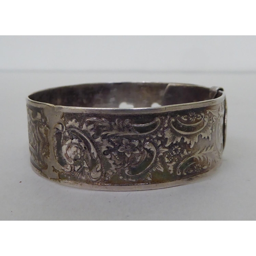 61 - A silver buckle bangle, decorated with floral motifs&nbsp; marks rubbed