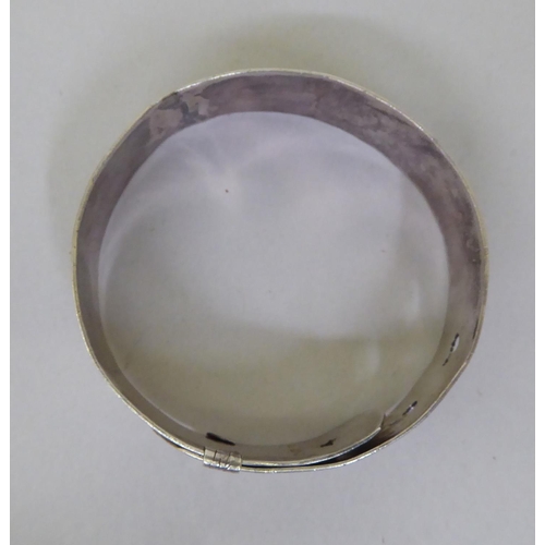 61 - A silver buckle bangle, decorated with floral motifs&nbsp; marks rubbed
