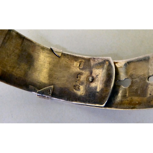 61 - A silver buckle bangle, decorated with floral motifs&nbsp; marks rubbed