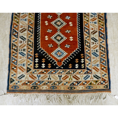 A Turkish rug, decorated with repeating designs, on a multi-coloured ...