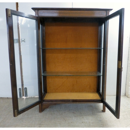2 - An Edwardian string inlaid mahogany, two door bookcase, enclosing two glazed shelves, raised on stra... 