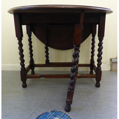 A mid 20thC oak drop leaf table, raised on block and barleytwist ...